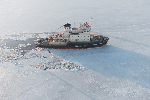 Vyborg, Russia - December 26, 2022: Diesel icebreaker Kapitan Izmailov moored in fast ice. Aerial view