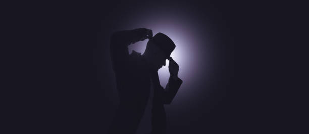A male performer adjusts his hat. Spotlight in the background.