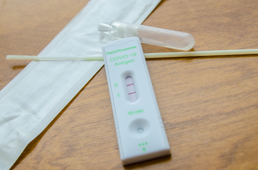 Positive Covid-19 Test Result over a wooden table
Cotton swab in background.