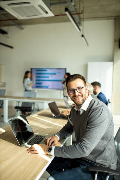 istock Cheerful businessman looking at camera while working on laptop 1453522862