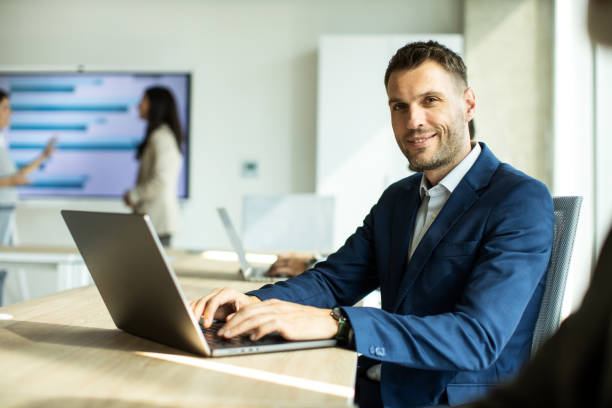 istock Cheerful businessman looking at camera while working on laptop 1453522876
