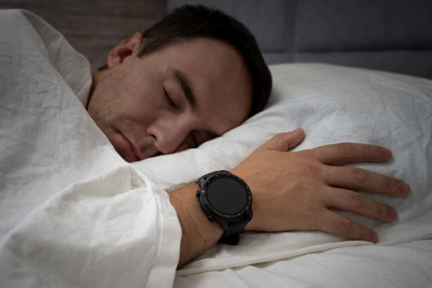 istock Man Sleeping With Smart Watch on Hand measuring Heartbeat Rate. empty screen on the clock for the dayz or test. copy space 1453523711