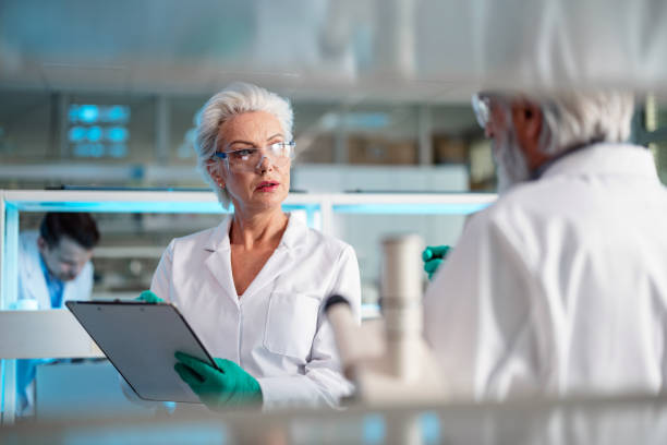 istock Senior Chemist Discussing With Colleague In Laboratory 1453524861