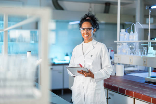 Smiling Female Scientist Noting Results Of Experiment In A Lab stock photo