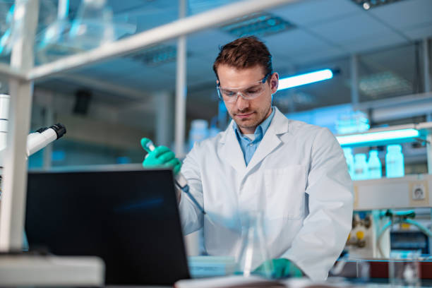 istock Caucasian Biochemist Mixing Liquid Chemical Using Pipette 1453524901