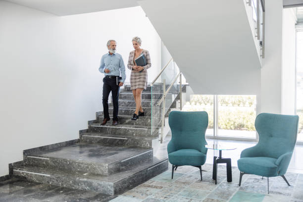 istock Two Senior Businesspartnes Walking Downstairs Talking To Each Other 1453524968