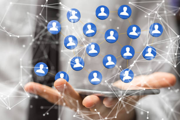 istock Illustrated network graphic with blue icons over a person's hand holding a phone 1453528126