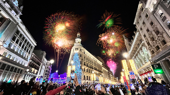 General landscape view of people enjoying and celebrating with fireworks New Year's Annual Fireworks Welcome Show at Plaza del Sol, Madrid, Spain.