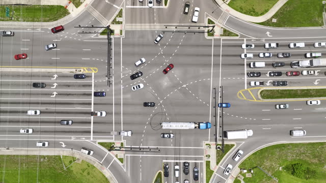 Aerial view of large multilane road intersection with traffic lights and moving cars and trucks