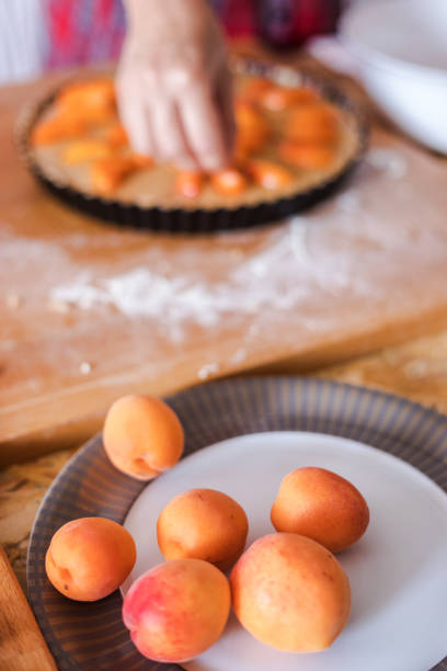 French cuisine, Apricot Frangipane Tart preparing, sprinkling dough with ripen fresh apricot slices, close-up, selective focus