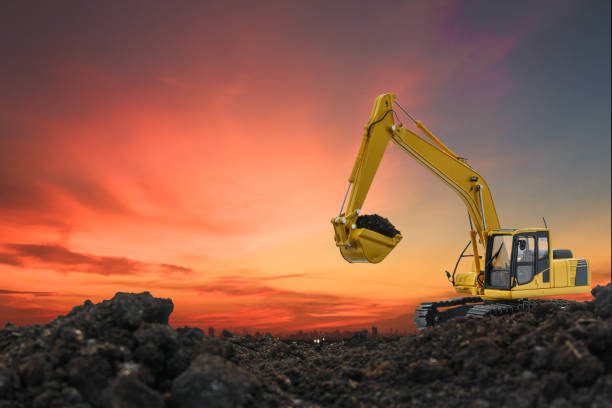 Excavators are digging the soil in the construction site on the orange  sky background