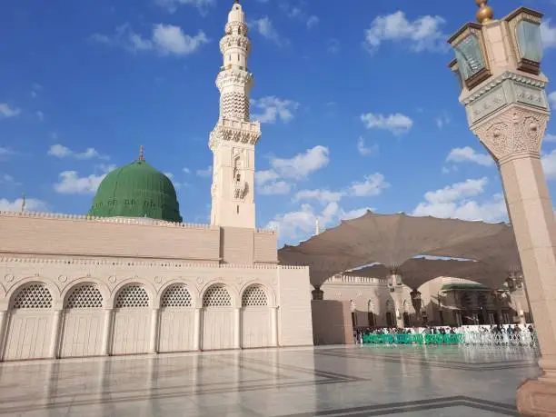 Beautiful daytime view of Masjid Al Nabawi, Medina's green dome, minarets and mosque courtyard.