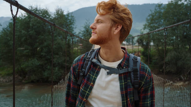 istock Hiker walking mountain valley bridge. Redhead guy enjoying adventure outside. 1453564669