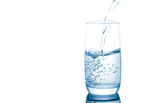 Pouring fresh mineral water into clear glass isolated on white background.