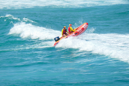 Volunteer lifesavers of Surf Life Saving NSW ride over a breaking wave during their patrol in an inflatable boat off Bondi Beach, Sydney on New Year's Day 2023.  This image was taken on a sunny afternoon from the cliffs on the southern end of the beach.