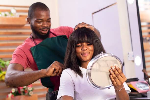 parrucchiere nigeriano che lavora sui capelli della donna in un salone - owner hair salon beauty spa female foto e immagini stock