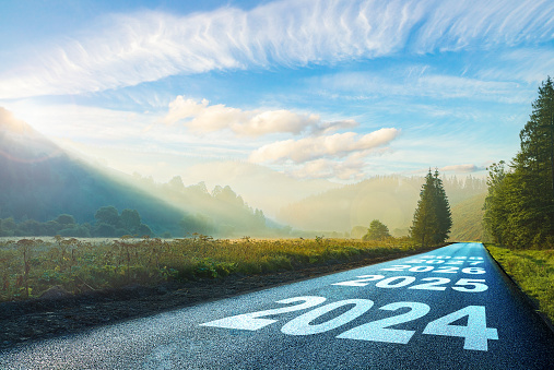 road on which is written 2024 at sunrise in the mountains ilis.beginning 2024. morning fog near the forest and mountains and road. 2025. 2026. 2027. 2028.