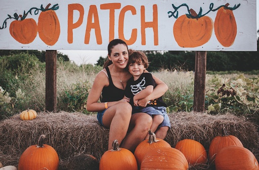 A young mom with her son sitting on a hale bale at a Pumpkin patch in Bonita Springs, Florida