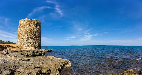 The Tower of Abbacurrente at a beach with calm water in Sardinia, Italy