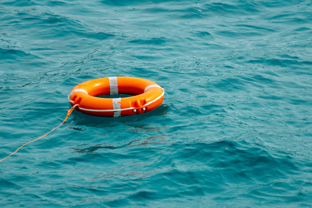 istock Orange lifebuoy floating on blue sea water 1453572047