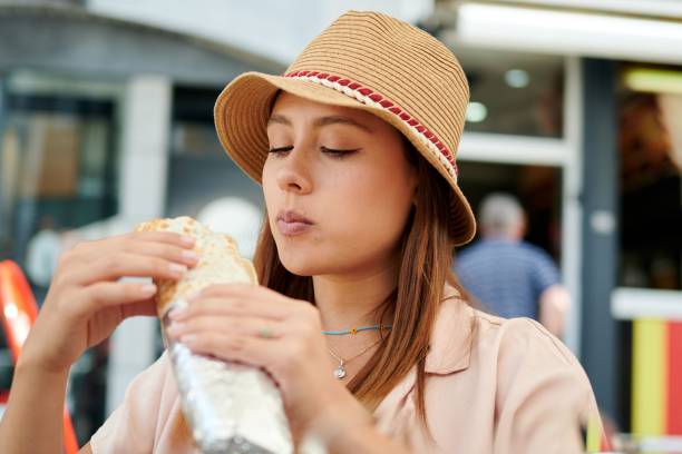 istock Hispanic woman eating a burrito in an open-air restaurant 1453572213