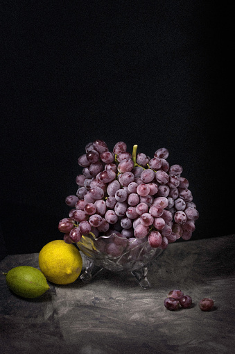 A closeup of grapes and lemons on a black background - still life