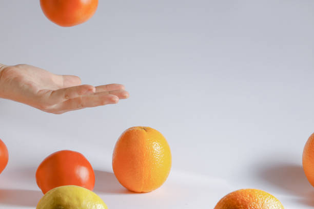 istock Hand playing with colorful oranges in a studio on a white background 1453572820