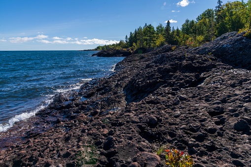 A scenic view of rocky shore of Lake Superior covere with greenery on the Keweenaw peninsula, Michigan