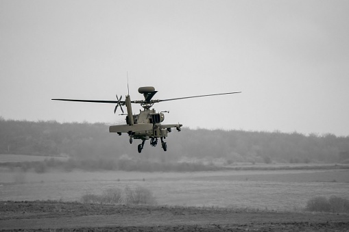 Army attack helicopter performing low level hover maneuver