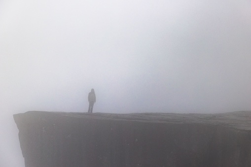 A person standing on the top of a hill on a gloomy day in misty weather