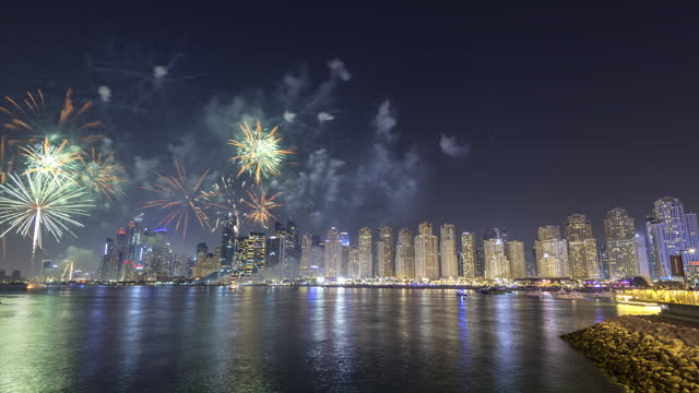 Time lapse of fire work show between Jumeirah beach and blue water al ain wheel at night.