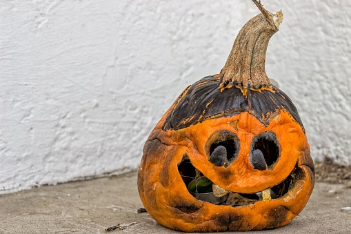 A rotting old carved jack-o-lantern on a patio