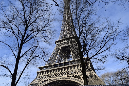 A low angle shot of the famous Eiffel tower in Paris against the blue sky during the daytime