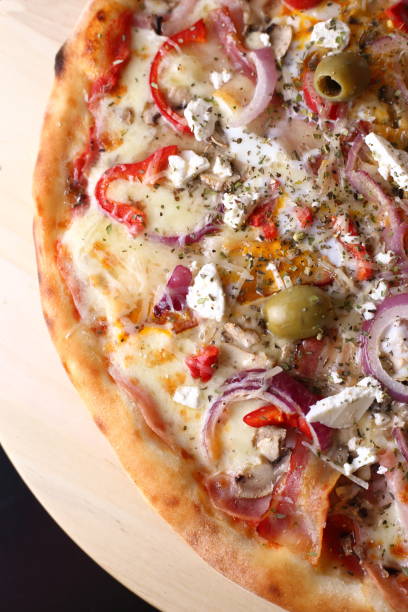 istock Partially seen appetizing pizza with tomatoes, green olive and onions dressed with the cheese 1453581010