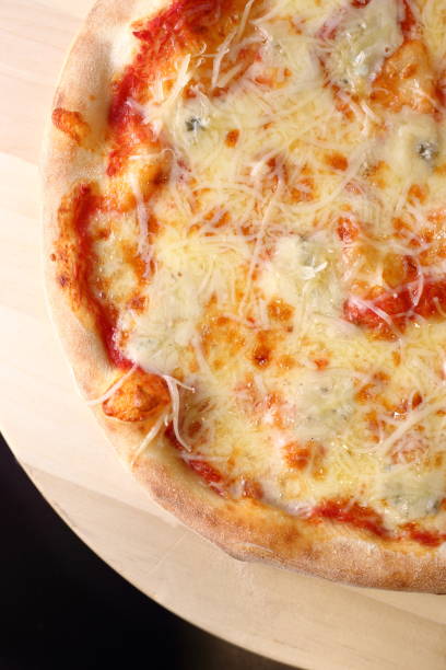 istock Appetizing pizza with tomato sauce dressed with the cheeses on a wooden tray 1453581075