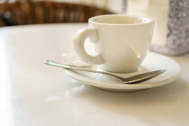 eine weiße tasse espresso auf einem teller mit einem löffel in einem café. speicherplatz kopieren - isolated on white breakfast cafe office stock-fotos und bilder