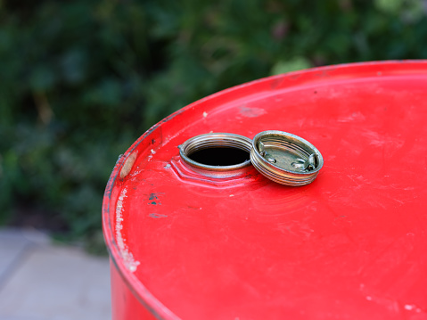 A close-up shot of the top part of a red barrel with the cap removed that is standing outdoors