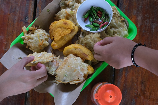 Indonesian fritters platter with hands picking some