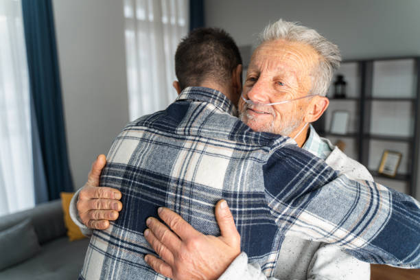 el hombre y su padre mayor abrazados - senior living communitiy fotografías e imágenes de stock