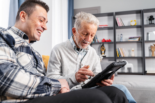 Senior man takes help in digital tablet from a young man