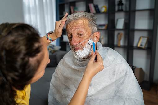 Volunteer in home visit at senior man,cares about his hygiene