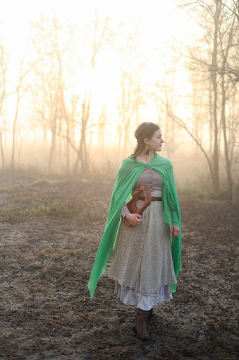 Young woman posing in a period costume in nature. About 25 years old, Caucasian brunette.