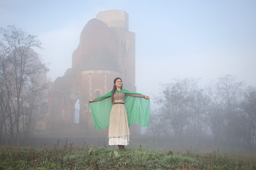 Young woman posing in a period costume in a medieval castle. About 25 years old, Caucasian brunette.
