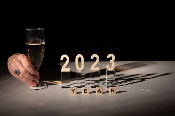 파리, 프랑스 - 12 31 2022: 한 여성이 샴페인 한 잔과 함께 2023년 새해를 기원합니다. - new years day celebration champagne coloured beige 뉴스 사진 이미지