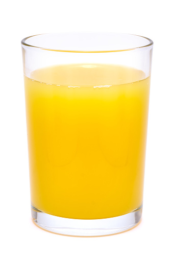 Front view of orange fruit and glass of orange juice on black background.