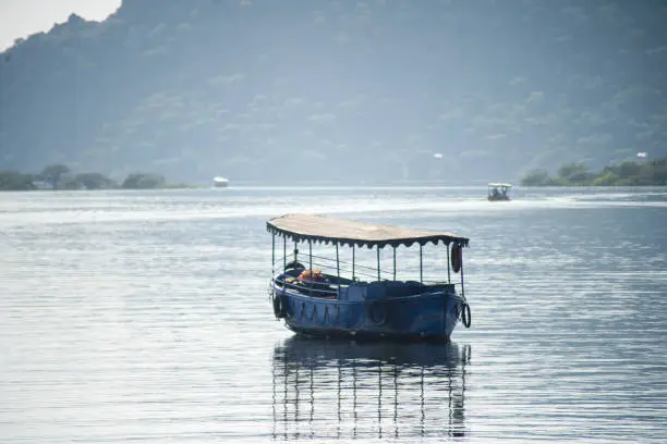 abandoned boat adrift marooned in the middle of water of lake pichola surrounded by aravalli hills in tourist city of udaipur rajasthan India