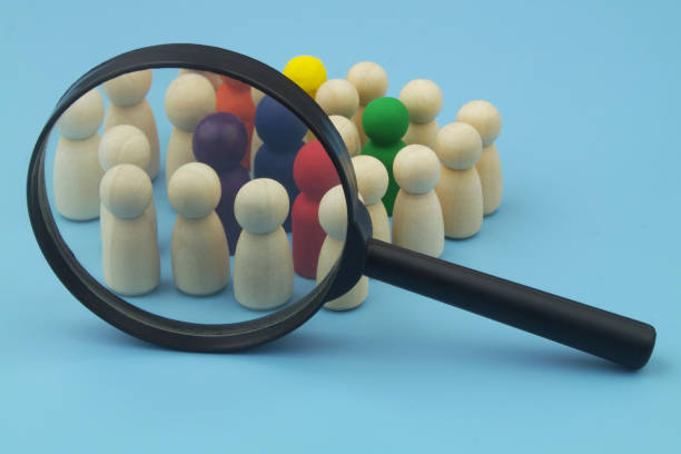 istock Group of not colored and colored people figures under magnifying glass  on blue. 1453614372