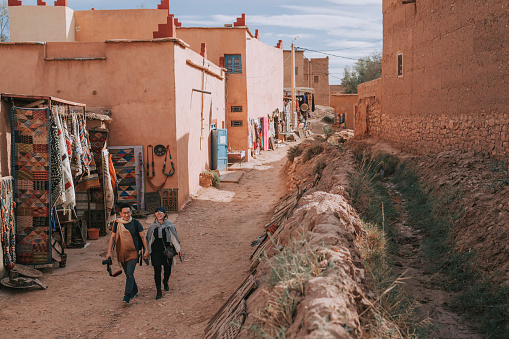 Asian Chinese tourist couple walking in alley of Ait Benhaddou, Ancient city Morocco North Africa