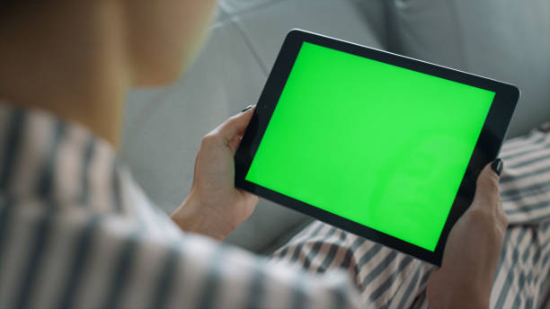 istock Girl watching green tablet screen closeup. Student resting on sofa enjoy blog 1453615721