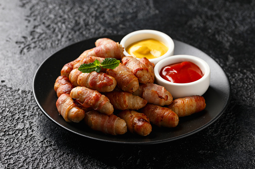 Pigs in blankets with ketchup and mustard sauce. Party food.